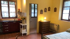 Een knus slaapkamer met een bed, een klein nachtkastje met een lamp, een radiator en een raam met gordijnen.