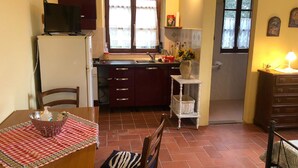 Een functionele keuken met een koelkast, een spoelbak en een eethoek met een tafel en stoelen.