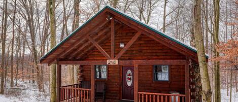 En stuga av trä med en veranda, en skylt med texten ”Curry Cabins” och en grund av sten.