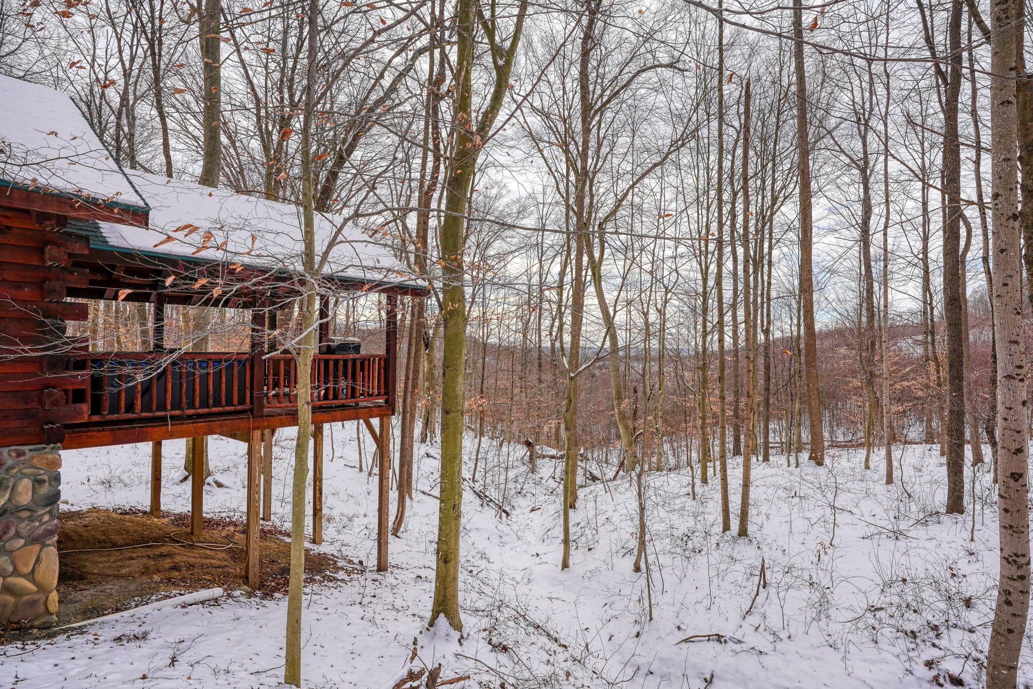 A wooden cabin with a balcony, surrounded by a snowy forest.