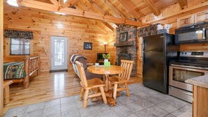 A wooden interior with a dining table, chairs, a refrigerator, and a stove.