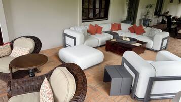 A living room with wicker furniture, a white sofa set, and a coffee table.