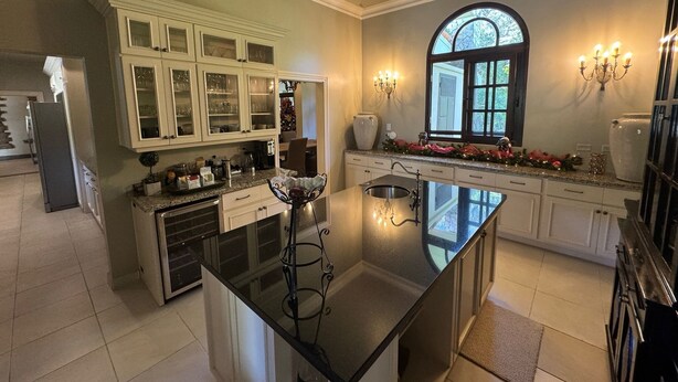 A spacious kitchen with a large island, white cabinetry, and a decorative window. - Boquete Luxury: Chic & Serene Home, Walk to Town & Amenities (Boquete)