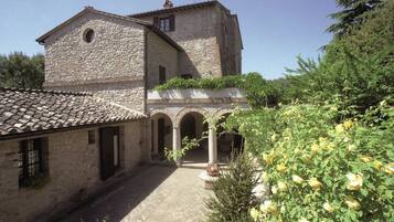 A stone building with a courtyard, arched passageways, and a rose bush.
