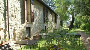 Un bâtiment en pierre doté d’une terrasse et agrémenté de plantes en pot.