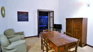 Un coin repas comprenant une table en bois, des chaises, un canapé et un meuble.