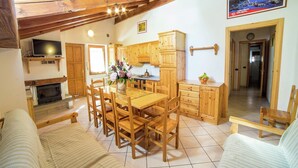 A cozy, well-lit room with wooden furniture, a fireplace, and a dining area.