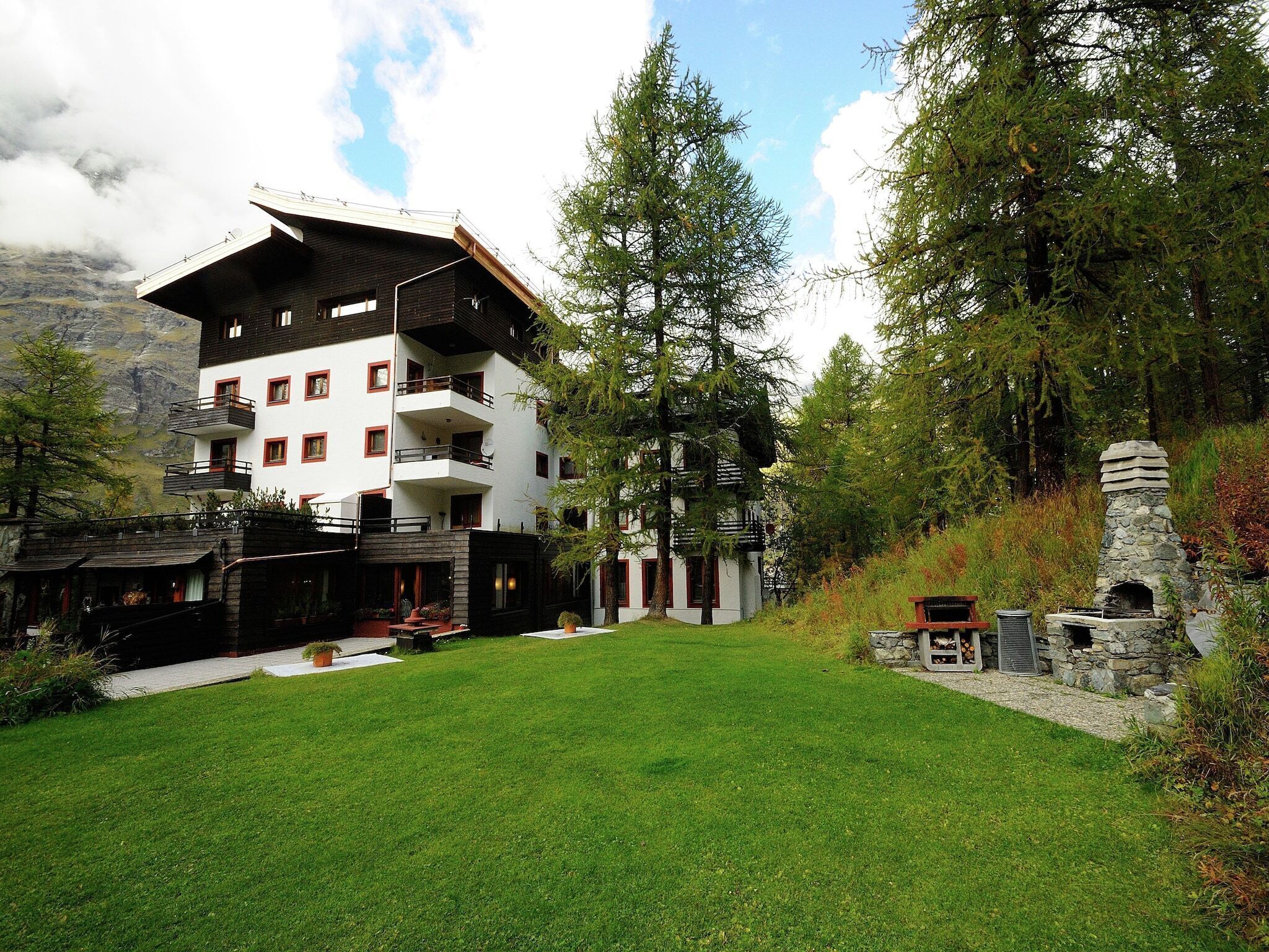 A multi-story building with balconies, a stone fireplace, and a well-maintained lawn.