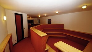 A hotel room with a red carpet, wooden benches, and a door.