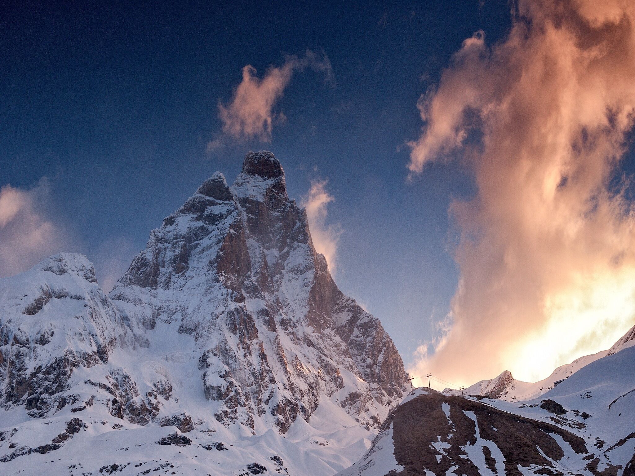 A snow-covered mountain peak with a clear sky and a sunset.