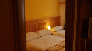 A room with two beds, wooden headboards, and a warm yellow wall.