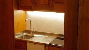 A compact kitchen with wooden cabinets, a stainless steel sink, and a built-in dishwasher.