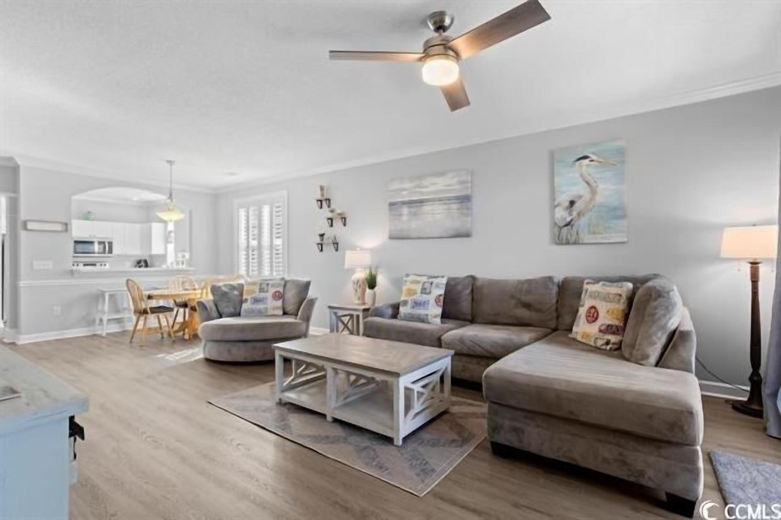 Un salon avec un canapé gris, une table basse et un ventilateur de plafond.