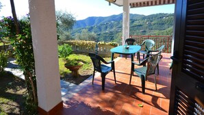 A terrace with a table and chairs, overlooking a mountainous landscape. - Escape Near Cinque Terre (Moneglia)