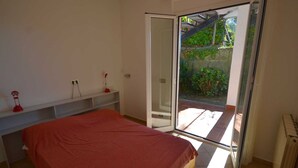 A bedroom with a bed, a desk, a chair, and a sliding glass door leading to a balcony. - Escape Near Cinque Terre (Moneglia)