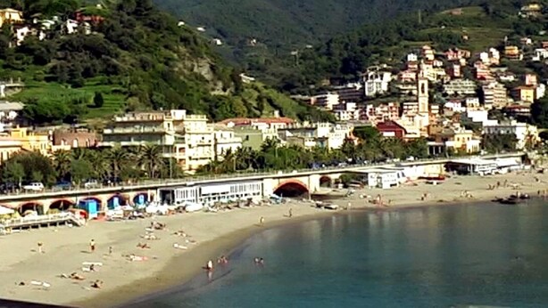 A coastal town with a beach, a bridge, and buildings on a hillside. - Escape Near Cinque Terre (Moneglia)