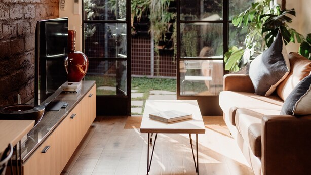 A modern kitchen with a wooden ceiling, a large window, and a sliding glass door leading to a garden. - Great 50 meter square architectural fitout with a cosy modern vibe to relax in  (Surf Beach)