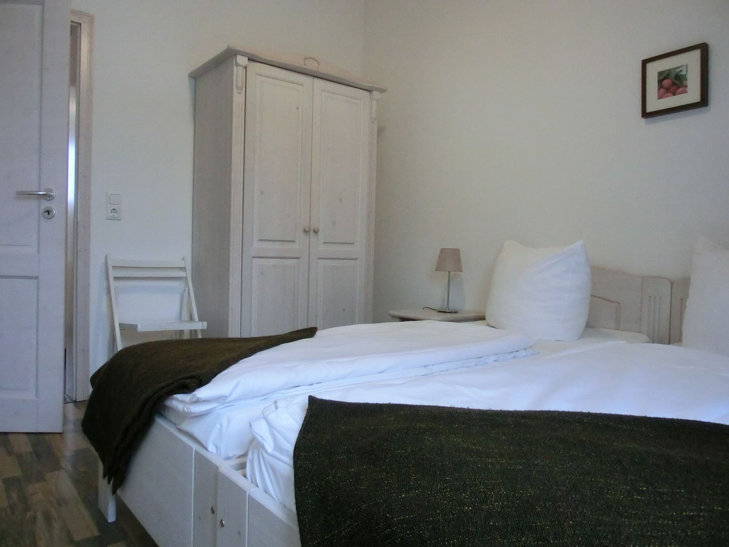 Un dormitorio con cama, mesita de noche, lámpara, armario y una silla.