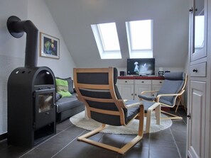 A modern living room with a fireplace, a sofa, two lounge chairs, a television, and a painting on the wall.