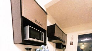 Una cocina compacta con microondas, estufa y armarios.