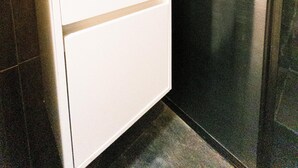 Un baño con un lavamanos blanco, un espejo encima y una cabina de ducha.