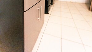Una cocina con gabinetes oscuros, una estufa y un lavabo. Hay una ventana con vistas al exterior.