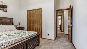 A bedroom with a large bed, a wooden wardrobe, and a hallway leading to another room.