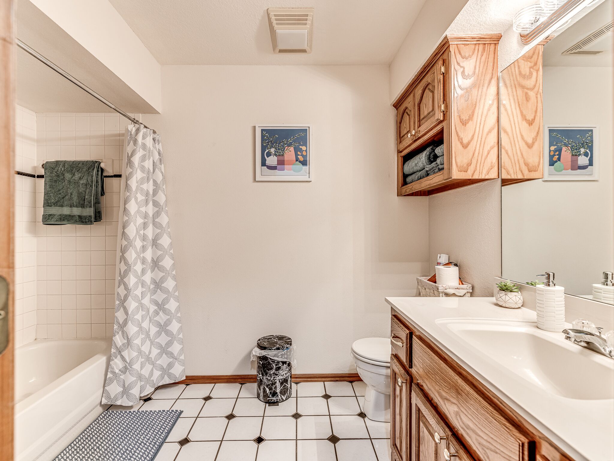 Un baño con bañera, inodoro y lavamanos. Hay toallas y un cubo de basura.