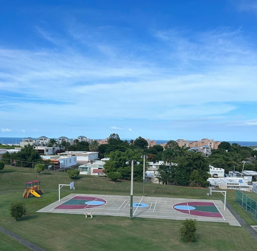 Ein Basketballplatz mit Spielplatz, umgeben von Gebäuden und Bäumen.