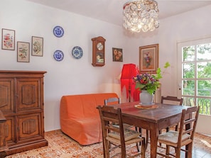 Un comedor con mesa de madera, sillas, un sofá rojo y ventana con vista a follaje.