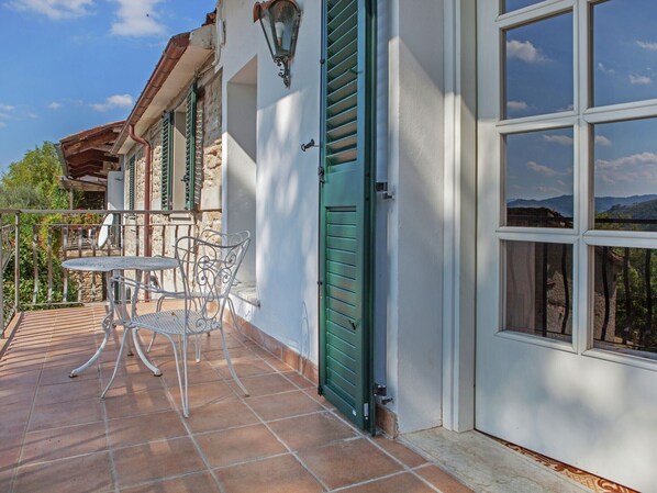 Una terraza con mesa y sillas, una puerta verde y vistas a las montañas.