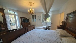Une chambre à coucher avec un grand lit, un lustre, une commode et un téléviseur.