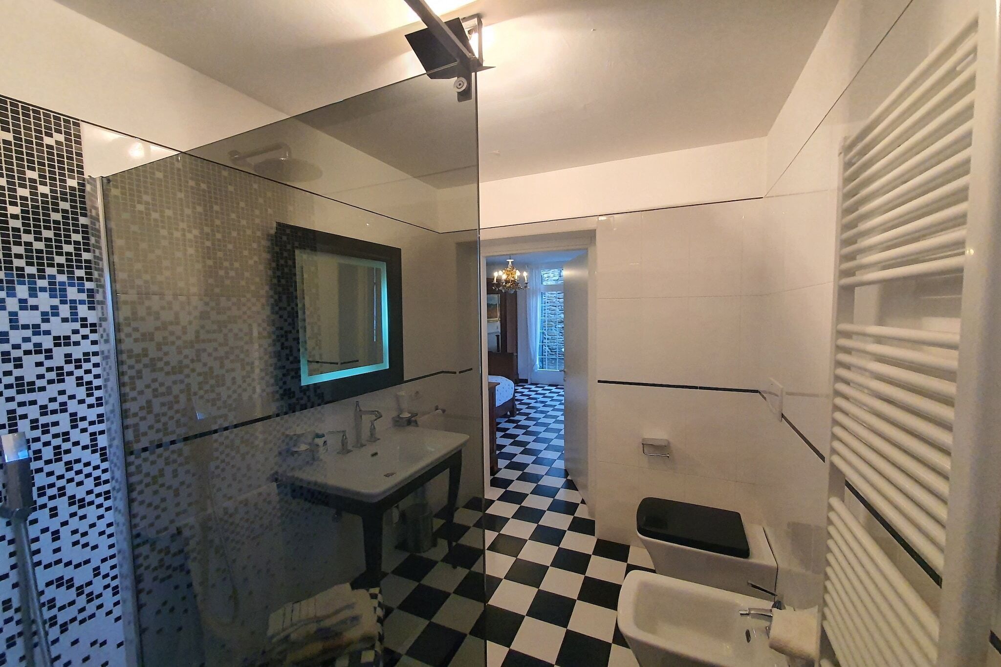 Un baño moderno con suelo a cuadros, cabina de ducha de vidrio, lavabo e inodoro.