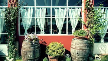 Un edificio con ventanas amplias, cortinas blancas y plantas en macetas.