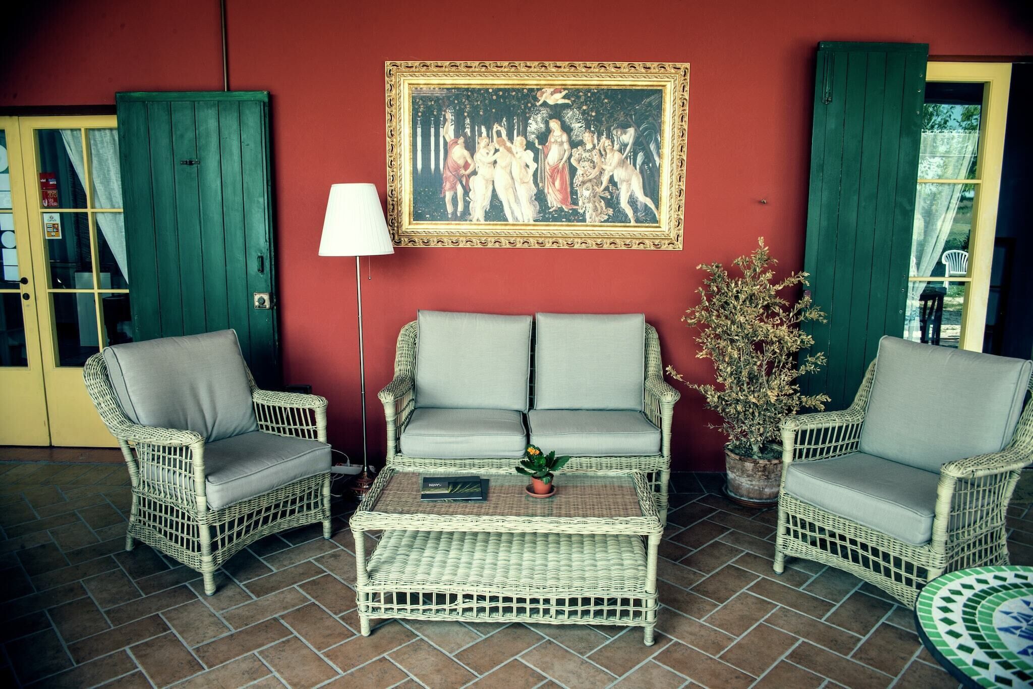 A wicker sofa set with a small table, a framed painting, and a potted plant.