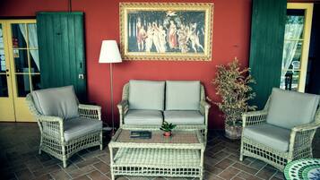 A wicker sofa set with a small table, a framed painting, and a potted plant.