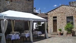 Un bâtiment en pierre surmonté d’un auvent blanc, avec des tables disposées à l’extérieur.