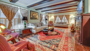 A spacious living room with a large red carpet, a white sofa, a wooden coffee table, and a fireplace. - Spacious Jamestown Home Near Nat'l Comedy Center! (Jamestown)