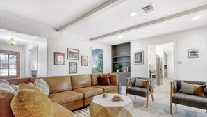 Ein großzügiges Wohnzimmer mit einem braunen Ledersofa, einem runden Couchtisch und einem grauen Sessel.