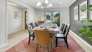 Ein Esszimmer mit einem langen Tisch, gedeckt für sechs Personen, umgeben von Stühlen.