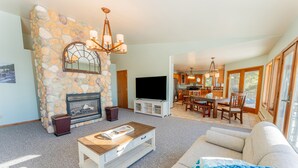 Una sala de estar con chimenea de piedra, televisor de pantalla plana y comedor con muebles de madera.