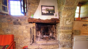 A stone fireplace with decorative ironwork, a framed picture above it, and a wooden bench to the left. - Farmhouse with pool,Ortignano (Ortignano)