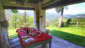 A table set outdoors with a red tablecloth, surrounded by stone walls and a scenic view of mountains and greenery. - Farmhouse with pool,Ortignano (Ortignano)