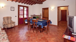 Un'area pranzo con tavolo e sedie in legno, una televisione su un mobile e un camino.