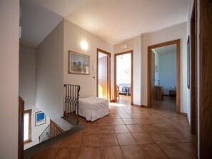 Ein Flur mit Treppe, einem Bett und einer Tür zu einem weiteren Raum.