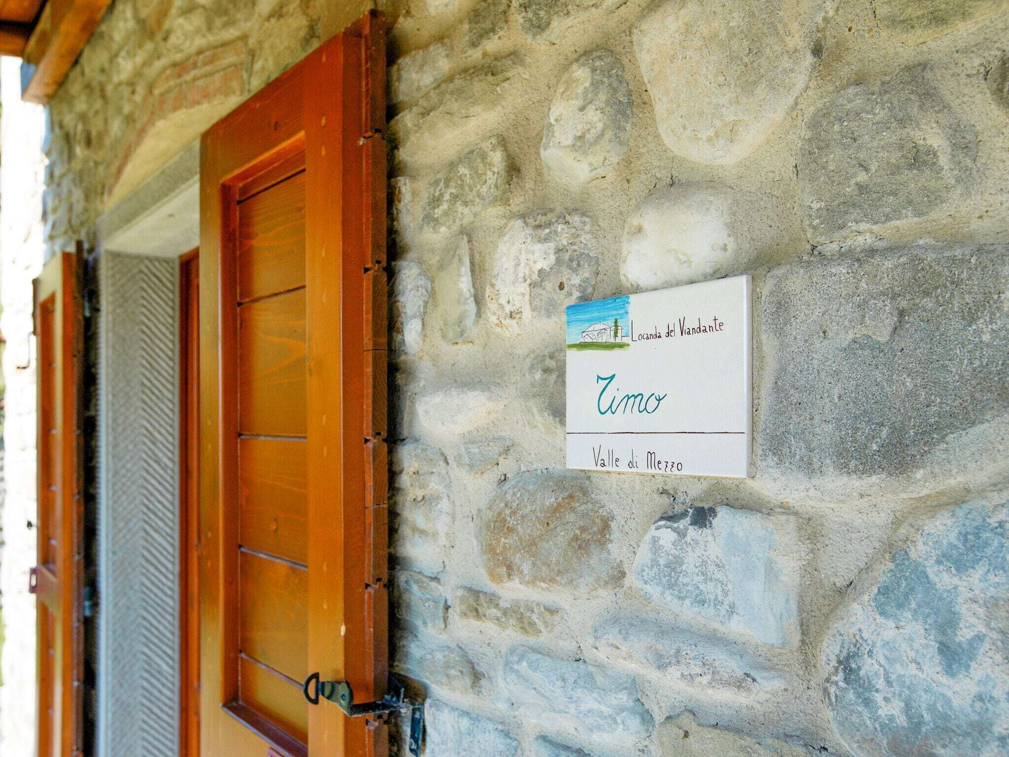 Eine Steinsäule mit einer Holztür und einem Schild, das 'Locanda del Vianante, Valle di Mezzano' anzeigt.