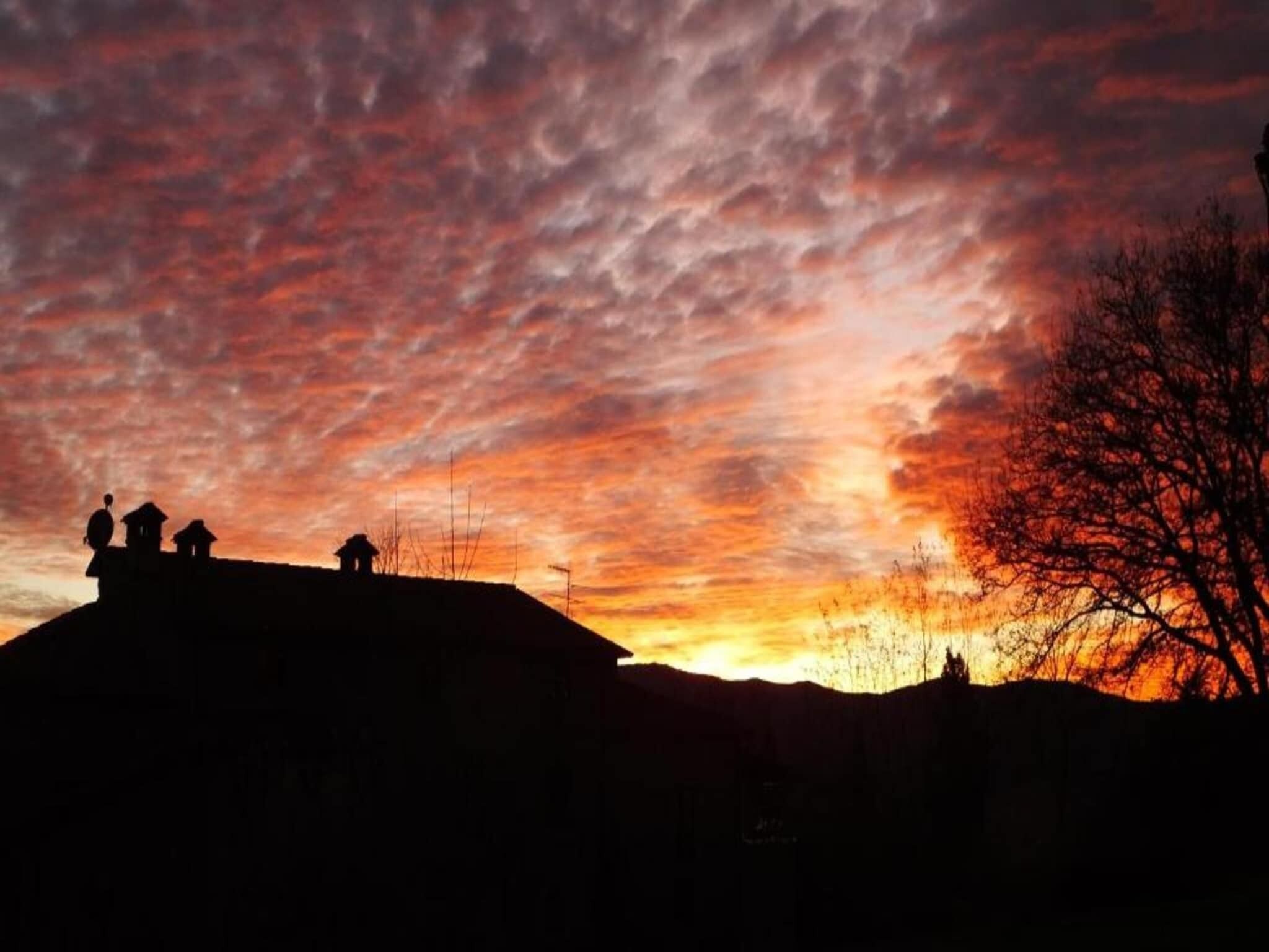 A silhouette of a hill with people and buildings against a sunset sky.
