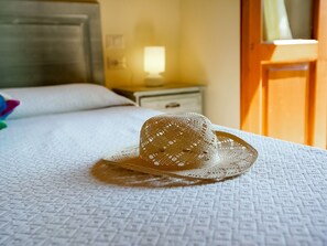 Ein Bett mit einem gewobenen Hut, ein Nachttisch und ein Beistelltisch.