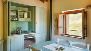 A kitchen with a dining table, cabinets, and a window with open shutters.