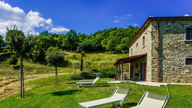 A stone building with a patio area featuring lounge chairs.